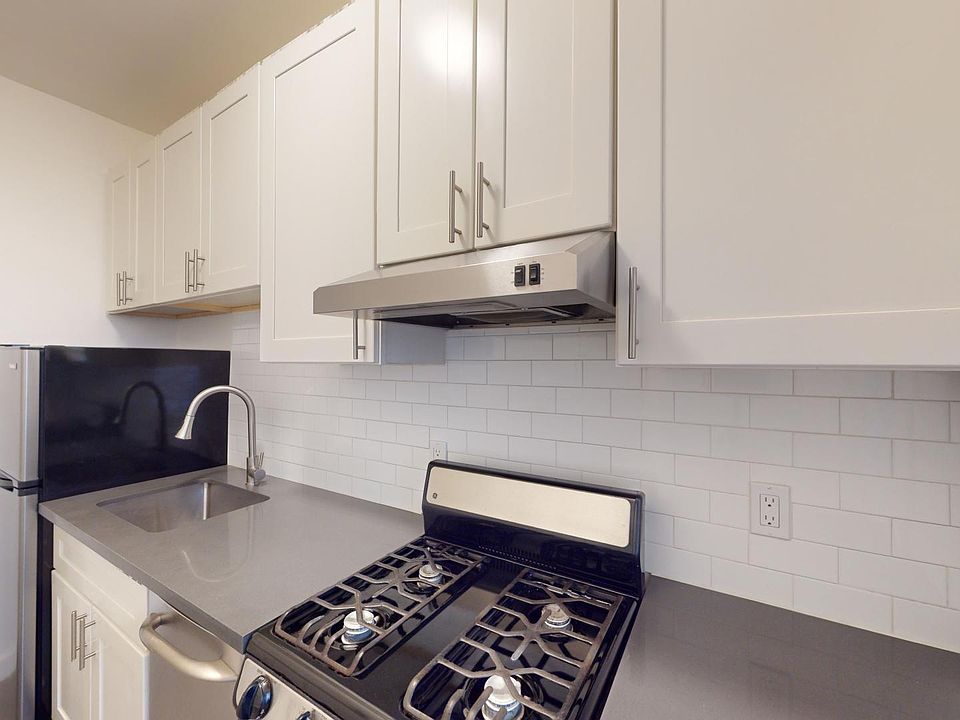 A modern kitchen with cabinets, stainless steel appliances, a sleek gas stove, and a glossy sink. The backsplash features subway tiles.