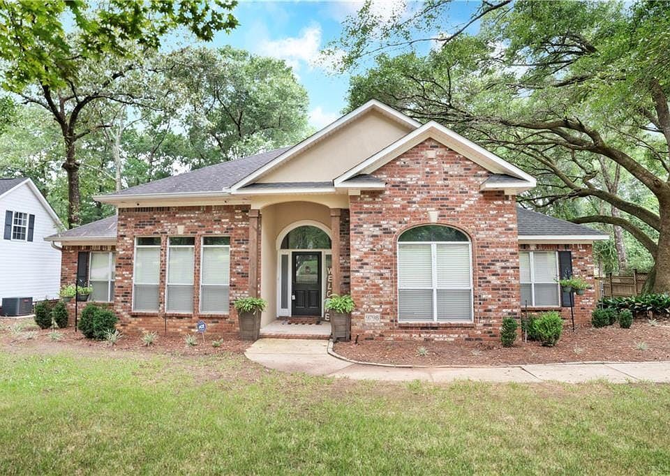 View of front facade with brick siding, a front lawn, and a shingled roof