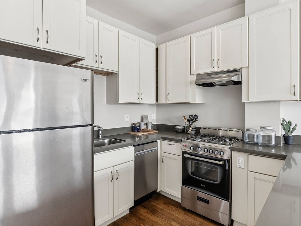 Kitchen with multiple cabinets, refrigerator, stove, range hood, and sink