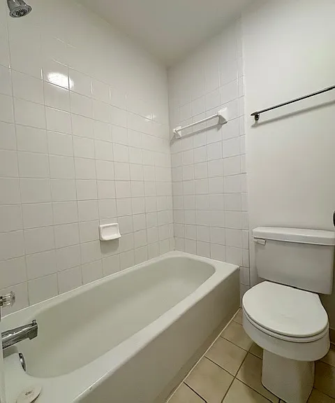 bathtub/shower and commoed with tiled walls and floor