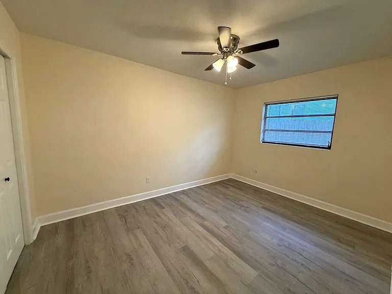 Secondary bedroom with ceiling fan, closet, and new flooring.
