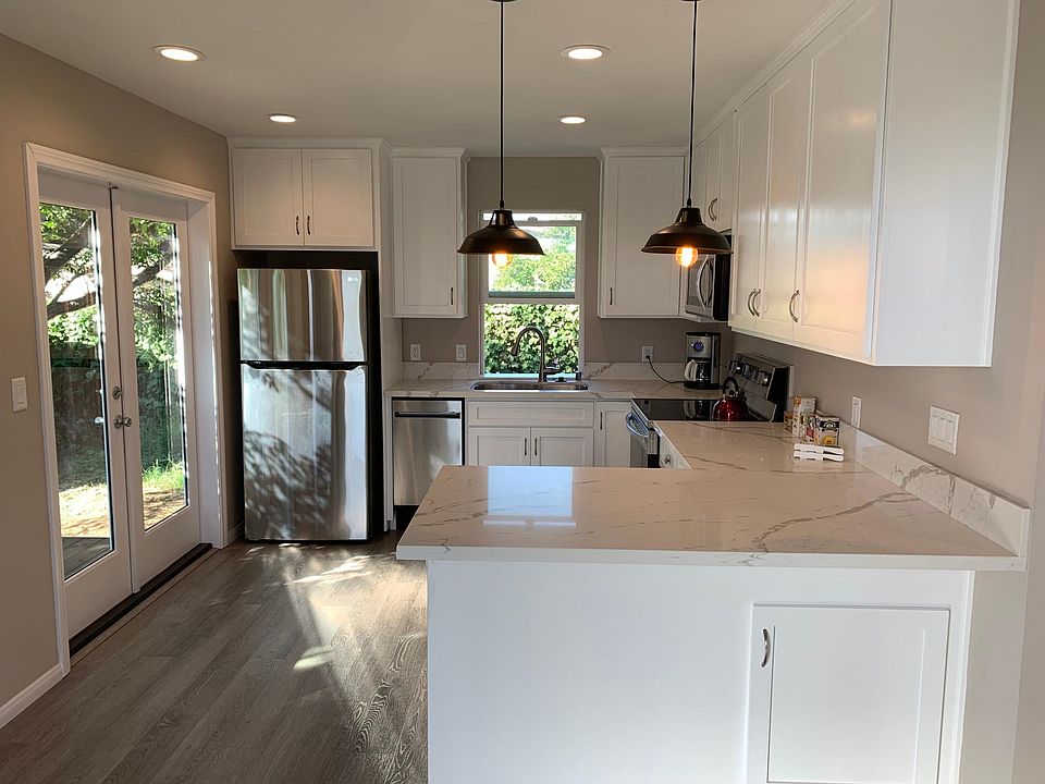 View of breakfast bar and kitchen with vintage lighting and natural light from French doors.