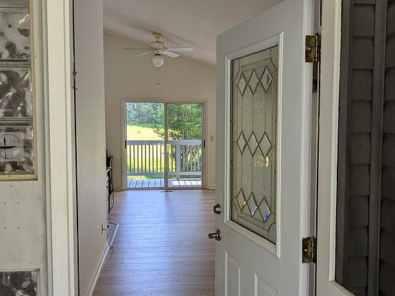 Front door entry showing deck in the background, with vaulted ceiling. The entry features custom art glass.