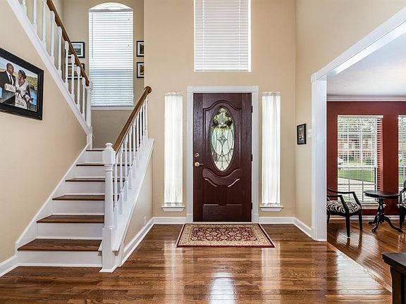 Gorgeous entry with wood floors and high ceiling.