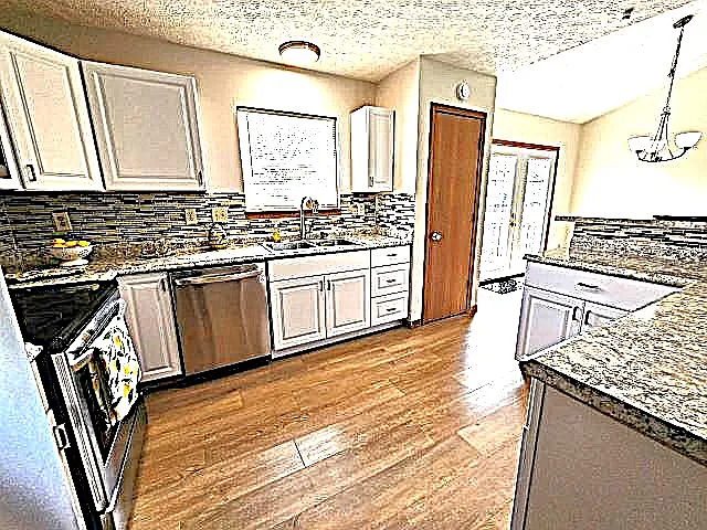 White kitchen cabinetry, countertops and stainless steel appliances + breakfast bar counter.