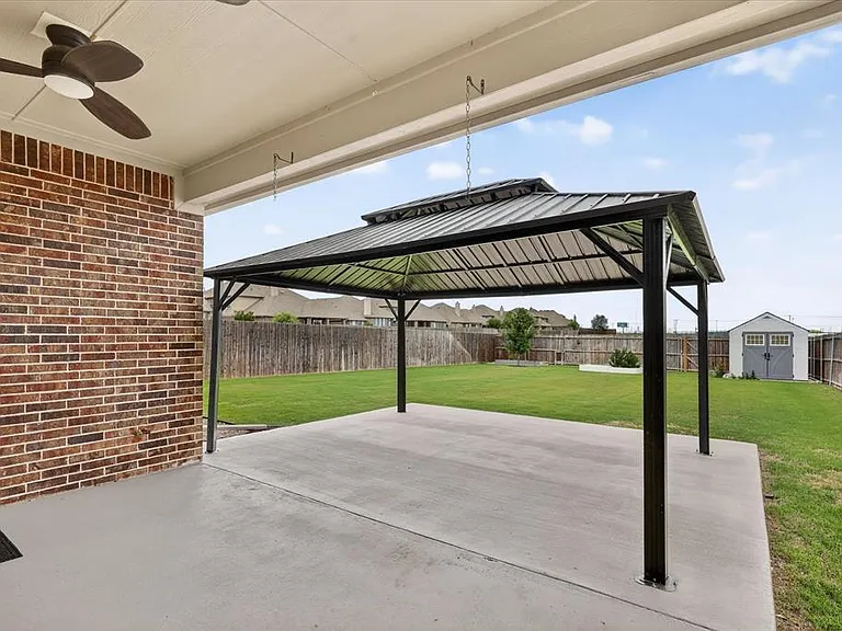 Covered patio featuring a ceiling fan, brick exterior, and concrete flooring