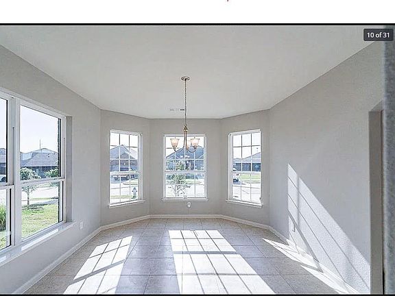 Unfurnished dining area with tile floors and a gorgeous chandelier.