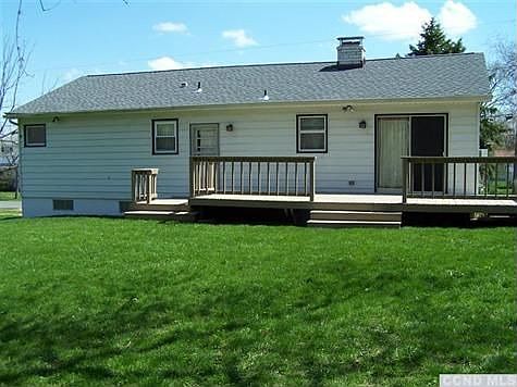 Backyard with large newly stained deck & woods to the back.