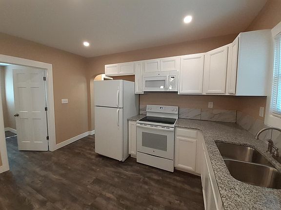 Kitchen with granite countertops, tile backsplash, plentiful cabinet space, dishwasher, and new appliances.