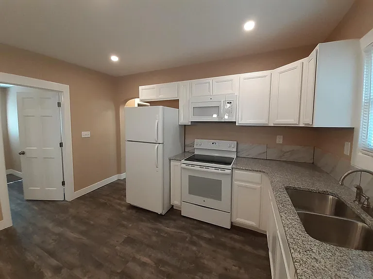Kitchen with granite countertops, tile backsplash, plentiful cabinet space, dishwasher, and new appliances.