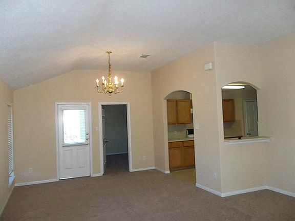 View from the front door looking through den towards formal dining, kitchen and master bedroom