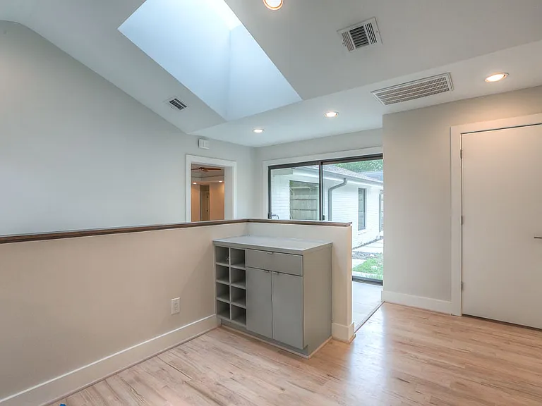 Vaulted exercise area or game room with skylight, built-in storage cubbies, and a slider opening to the rear deck