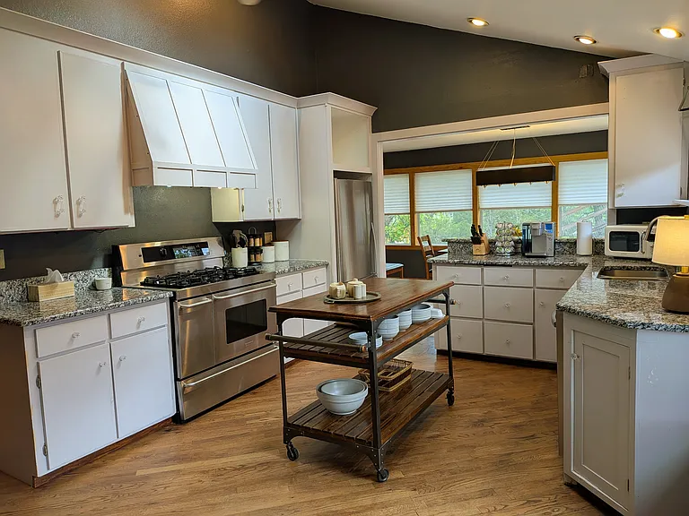 Kitchen with granite counters, stainless appliances, 5 burner gas stove with 2 ovens, and casual seating area.