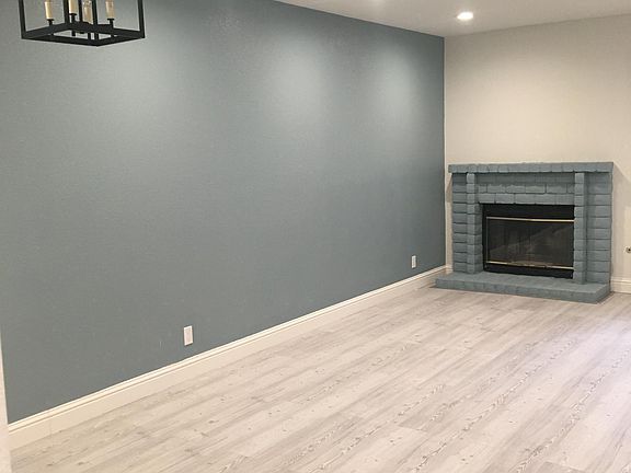 Spacious living room with new laminated wood floor, light fixtures, and ceiling lights