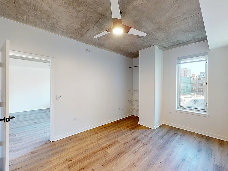 Spacious apartment bedroom with wood-style flooring.