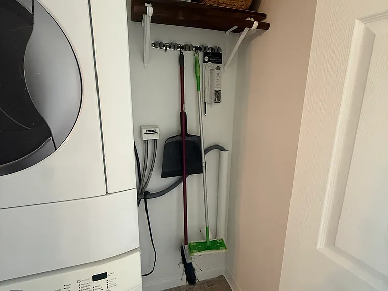 Hallway laundry/cleaning closet with in-unit stackable washer and dryer
