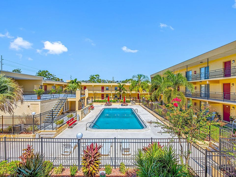 Vibrant apartment community featuring a luxurious outdoor pool, surrounded by lush tropical landscaping and modern amenities.