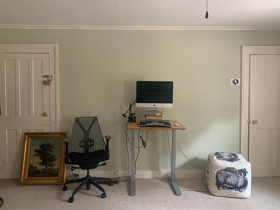 Across from couch. Door at left exits to stairway and front door. Door to right is walk-in closet.