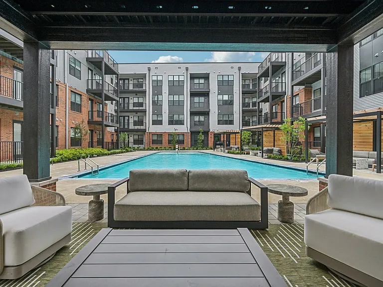 Elegant apartment complex featuring a luxurious pool and modern outdoor seating, perfect for relaxation and leisure.