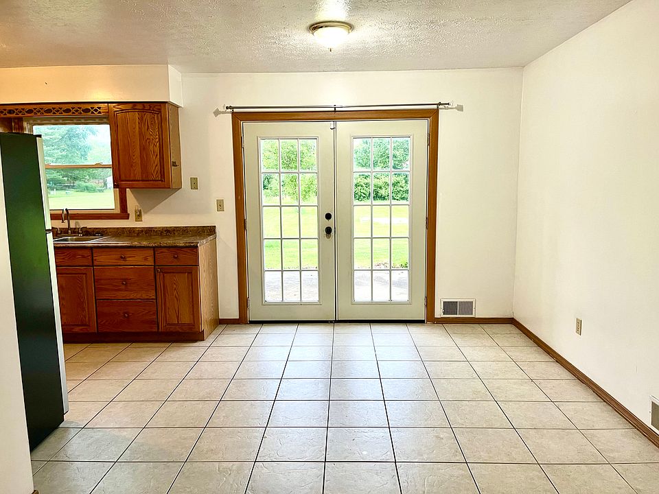 Tiled kitchen and living area. Double doors lead to back porch and wooded backyard