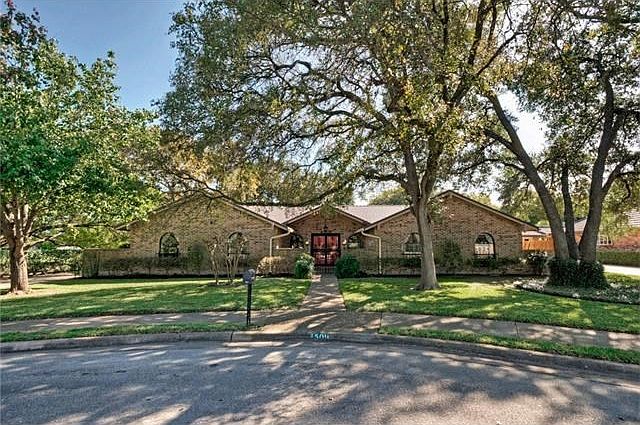 At the end of a quiet cul-de-sac, this handsome brick home is shaded by epic, spreading oak trees.