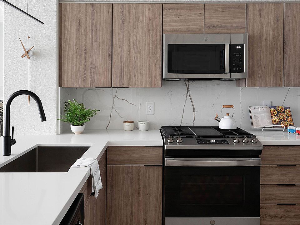 Apartment kitchen with stainless steel appliances, quartz countertops, and wood-style flooring.