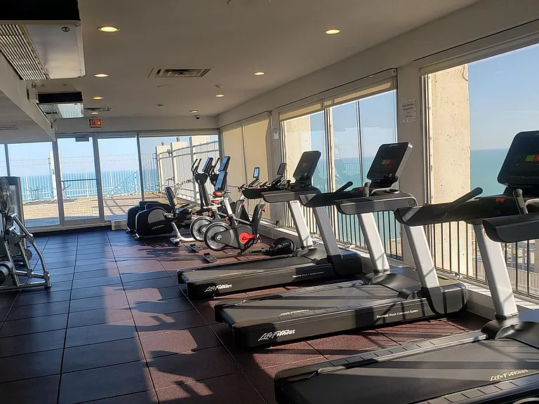 Gym with view of lake and skyline.