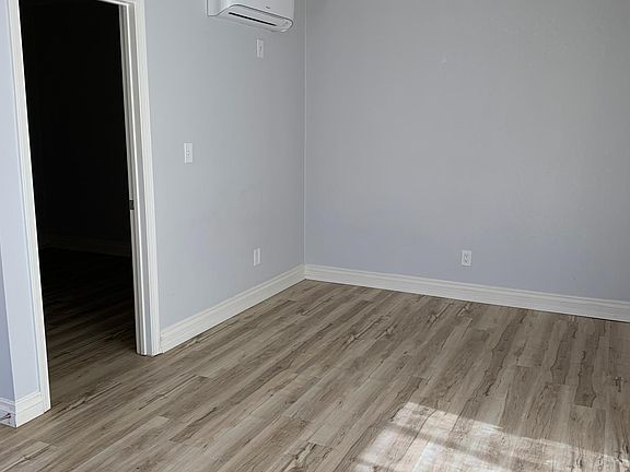 Living area features A/C wall unit leading to bedroom