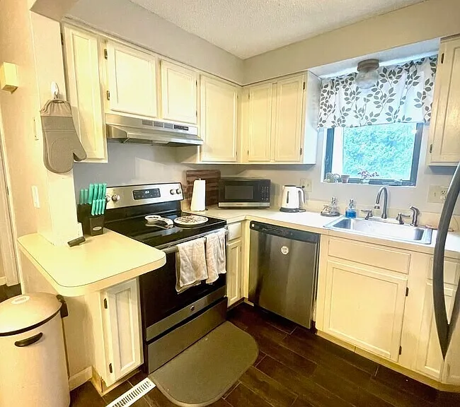 Kitchen view showing the stove, dishwasher, sink, and window over the counter.