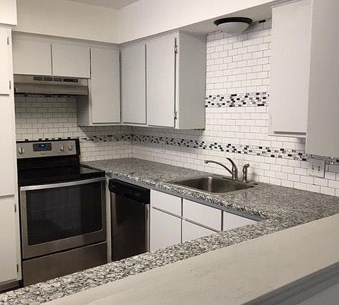 Kitchen features stainless steel with granite and subway til