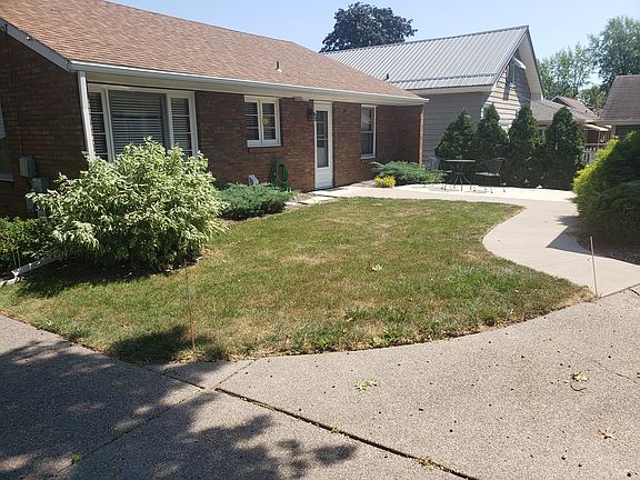 Yard between house and garage. Concrete Patio sitting area with table and chairs.