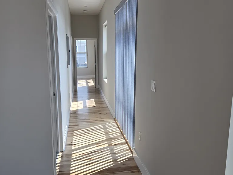 Hallway from living area to bedrooms and bathrooms. (Full guest bath immediately on left, bedroom 2 at opposite end of hallway, primary bedroom at left just before guest room.)