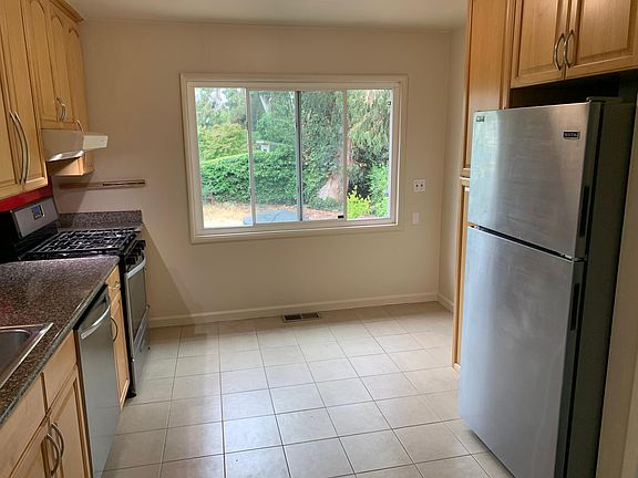 Kitchen off of living room with tile floor, maple cabinets and full size fridge