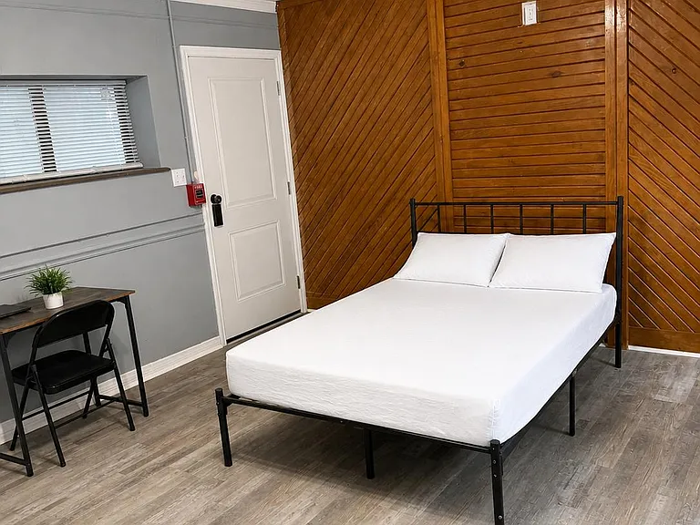 Furnished bedroom with full bed, dedicated desk space, ceiling fan lighting, and durable wood-look flooring.