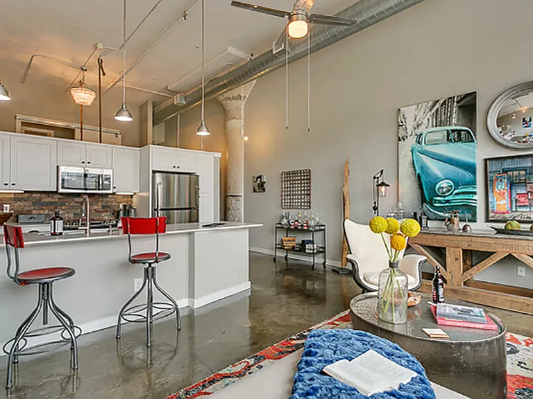 Living room with open concept kitchen, concrete floor, and beautiful white cabinets. Loft style apartment