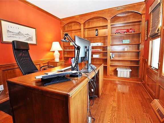 Private home office with custom adjustable shelves, wainscoting and custom window treatments,