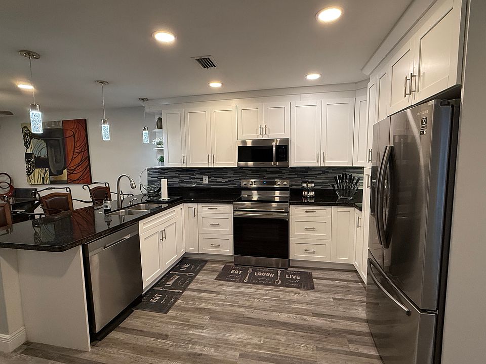 Chef Kitchen with airfryer, coffee/tea station, stainless steel dishwasher, microwave, fridge a freezer combo, granite counter top, pantry, garbage disposal with pendant lighting and under the counter lighting.