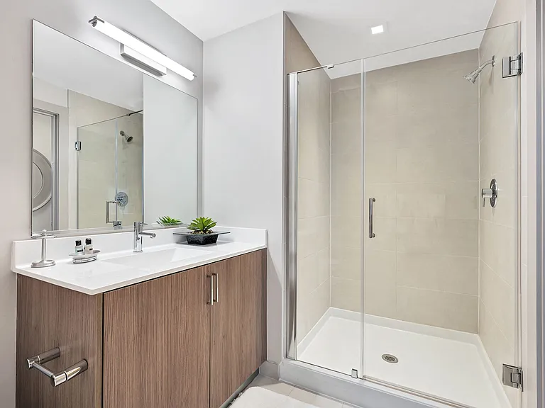 Quartz countertops and Italian style vanity in bathrooms with glass shower in select apartment homes