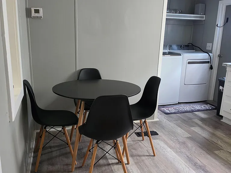Compact dining nook with a round table and seating for four, set on durable plank flooring near the laundry area.