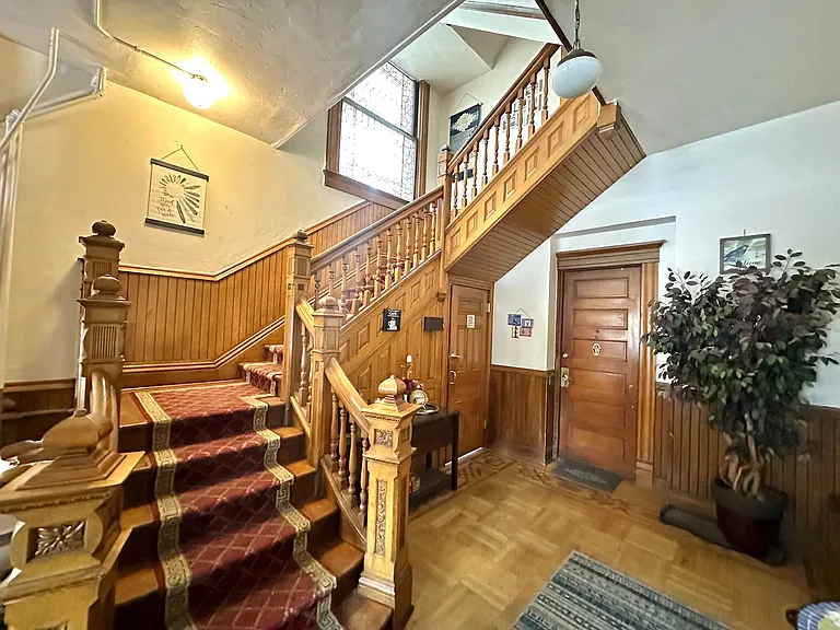 Experience timeless elegance in this inviting apartment entrance featuring a beautifully crafted wooden staircase.