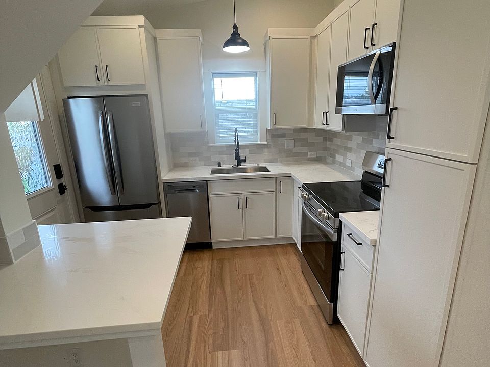 View into the kitchen from the living area. Full size refrigerator with icemaker, Dishwasher, sink with pull out faucet and garbage disposal, electric range/oven and microwave range/hood. Built in trash pull out in cabinets