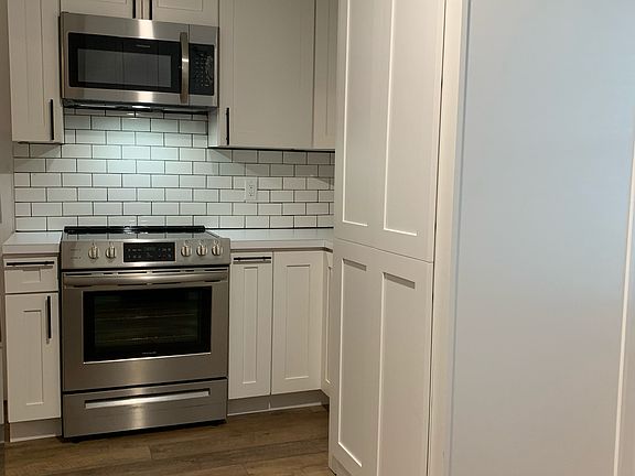 Stainless steel Samsung slide in oven & microwave; large cabinet on right houses the washer/dryer