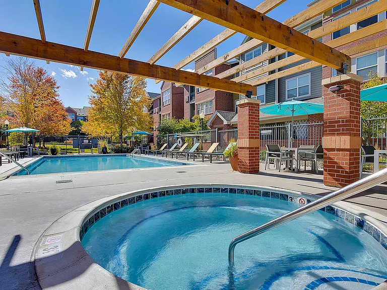 Inviting outdoor pool area with sun loungers, vibrant autumn trees, and stylish pergola, perfect for relaxation and leisure.