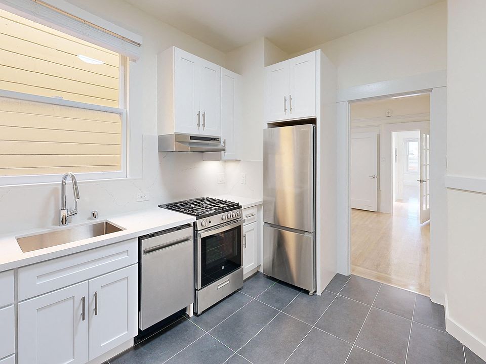 Kitchen with multiple cabinets, refrigerator, stove, range hood, and sink