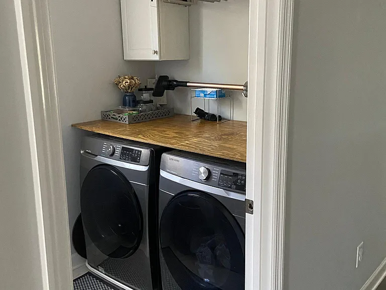 Laundry room with new Samsung front-load washer and dryer, and custom-built cabinets and drying rod