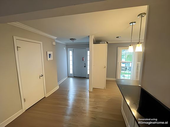 View of front door, powder room, and kitchen from the living room.