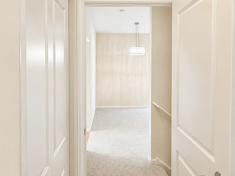 View of the dining room from the primary suite. Linen closet on the left; stairway to the basement on the right.
