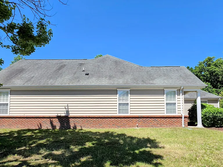 Elegant low-maintenance vinyl siding accented by a classic brick water-table facade and bright architectural windows.