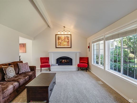 The lovely formal living room features a beautiful fireplace, wall of windows and showy exposed beam, vaulted ceiling.