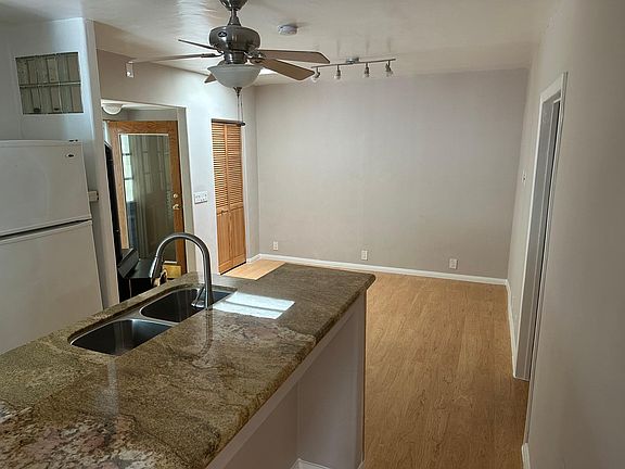 Side view of granite topped kitchen countertops with undermount stainless steel sink. View of living area.